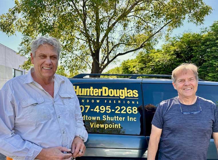 Two smiling men posing for a photo with the company vehicle